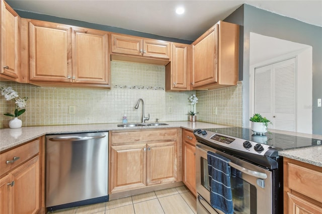 kitchen with light stone counters, decorative backsplash, light tile patterned floors, stainless steel appliances, and a sink