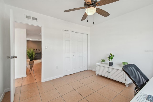 home office featuring light tile patterned floors, visible vents, baseboards, and a ceiling fan