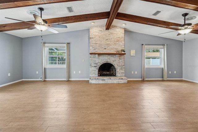 unfurnished living room featuring a brick fireplace, lofted ceiling with beams, light hardwood / wood-style floors, and ceiling fan