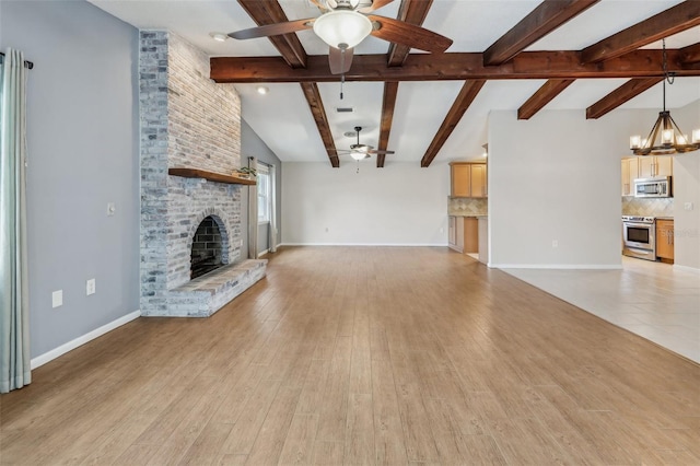 unfurnished living room with a fireplace, ceiling fan with notable chandelier, light hardwood / wood-style flooring, and vaulted ceiling with beams