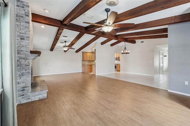 unfurnished living room with a brick fireplace, ceiling fan with notable chandelier, lofted ceiling with beams, and light hardwood / wood-style floors