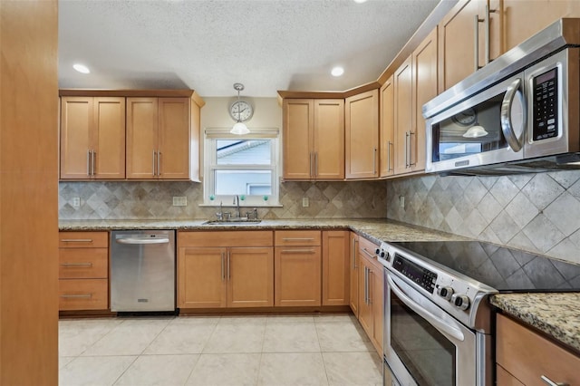 kitchen with sink, light stone counters, decorative light fixtures, light tile patterned floors, and stainless steel appliances