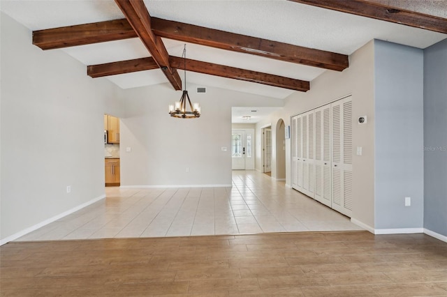 spare room with an inviting chandelier, light hardwood / wood-style floors, and lofted ceiling with beams