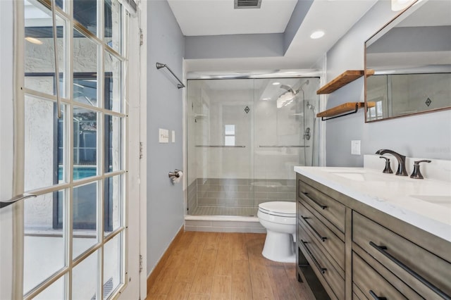 bathroom with walk in shower, vanity, toilet, and wood-type flooring