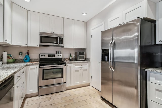 kitchen with white cabinetry, appliances with stainless steel finishes, and light stone countertops