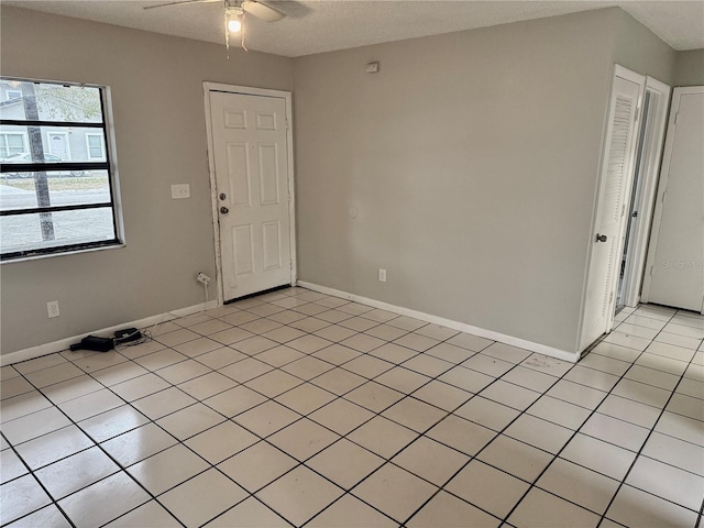 tiled empty room with a textured ceiling and ceiling fan