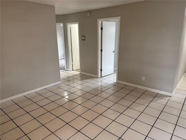 unfurnished room featuring light tile patterned flooring and a textured ceiling