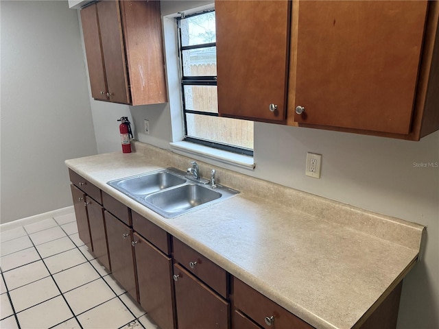 kitchen with dark brown cabinetry, sink, and light tile patterned floors