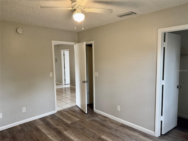 unfurnished bedroom with hardwood / wood-style flooring, ceiling fan, and a textured ceiling