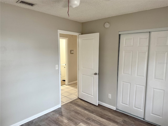 unfurnished bedroom with wood-type flooring, a closet, and a textured ceiling