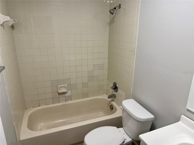 bathroom with tiled shower / bath combo and toilet