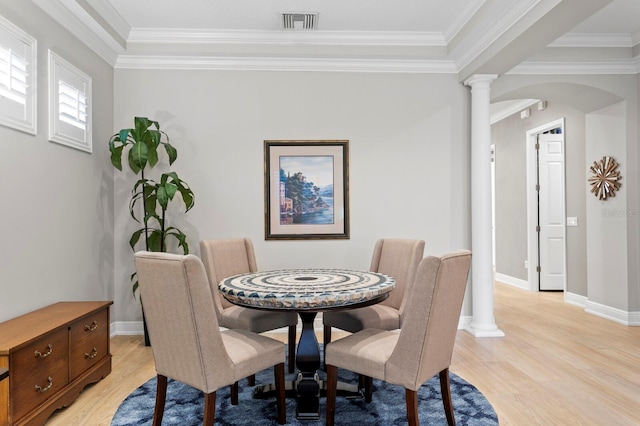 dining room with decorative columns, crown molding, and light hardwood / wood-style floors