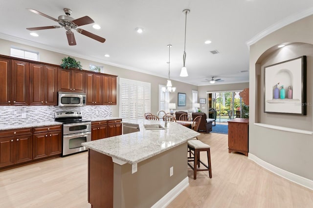 kitchen featuring pendant lighting, sink, stainless steel appliances, an island with sink, and a kitchen bar