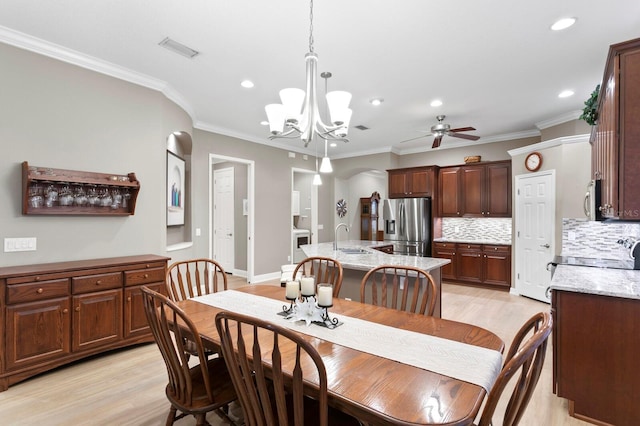 dining area featuring sink, crown molding, ceiling fan with notable chandelier, and light hardwood / wood-style floors