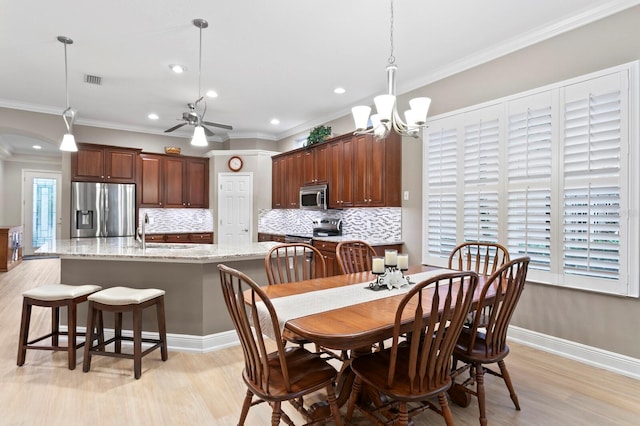 dining room featuring sink, crown molding, and light hardwood / wood-style floors