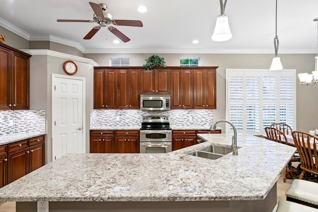 kitchen featuring sink, a breakfast bar area, hanging light fixtures, a center island with sink, and appliances with stainless steel finishes