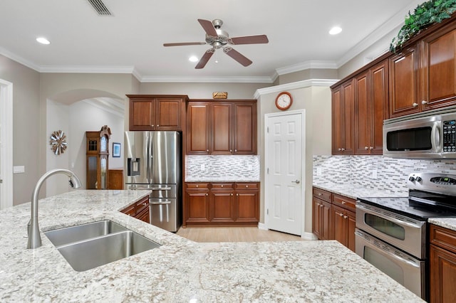 kitchen with light stone counters, appliances with stainless steel finishes, crown molding, and sink