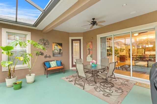 sunroom with beam ceiling, a skylight, and ceiling fan