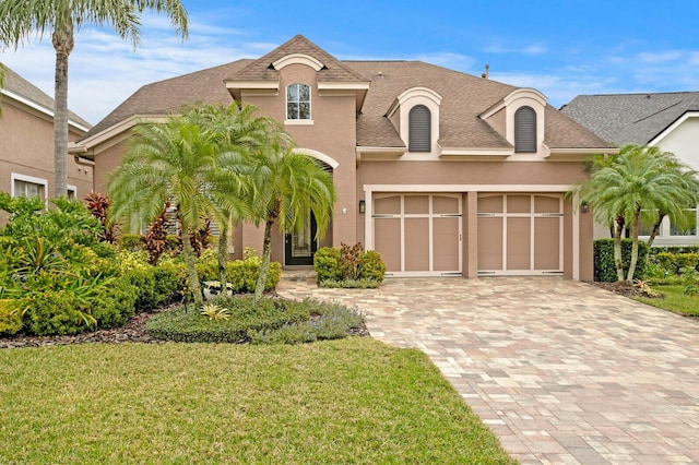 french provincial home with a garage and a front yard