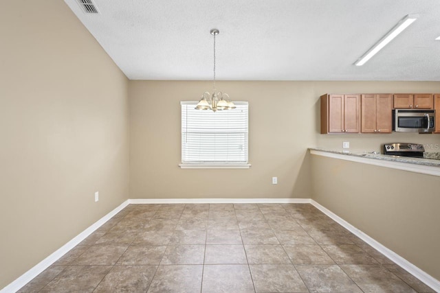 interior space featuring an inviting chandelier, hanging light fixtures, light tile patterned floors, stainless steel appliances, and a textured ceiling