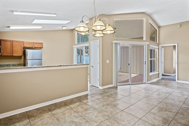 unfurnished dining area featuring lofted ceiling with skylight, light tile patterned flooring, and a textured ceiling