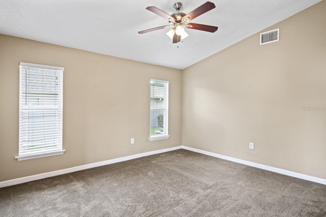 carpeted spare room with a textured ceiling, vaulted ceiling, and ceiling fan