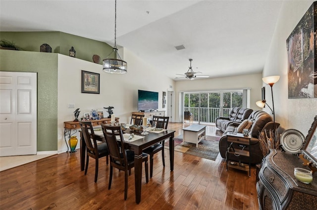 dining space with vaulted ceiling, dark wood-type flooring, and ceiling fan with notable chandelier