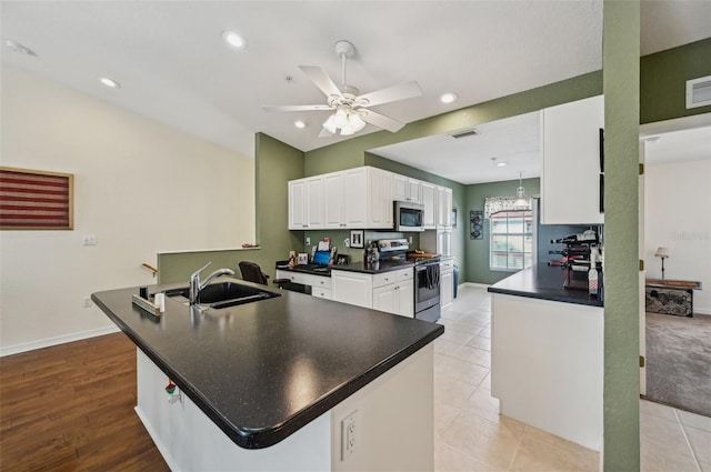 kitchen with appliances with stainless steel finishes, white cabinetry, sink, ceiling fan, and kitchen peninsula