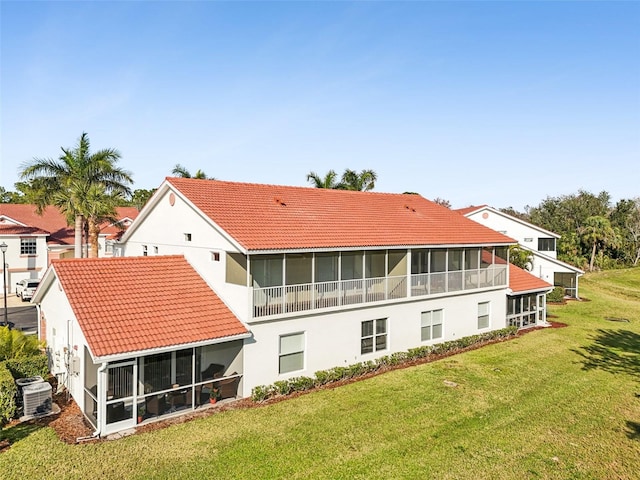 rear view of house with a sunroom and a lawn