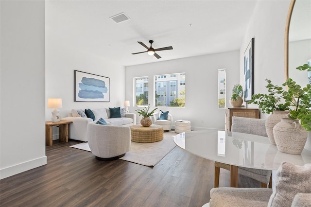 living room featuring dark wood-type flooring, visible vents, ceiling fan, and baseboards