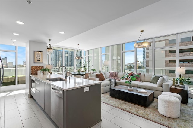 kitchen with expansive windows, dishwasher, hanging light fixtures, and a center island with sink