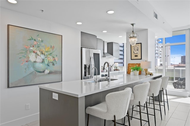 kitchen featuring pendant lighting, sink, backsplash, stainless steel refrigerator with ice dispenser, and a kitchen bar