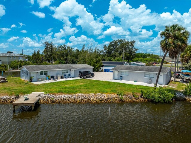 back of property with a yard, a water view, and a patio area