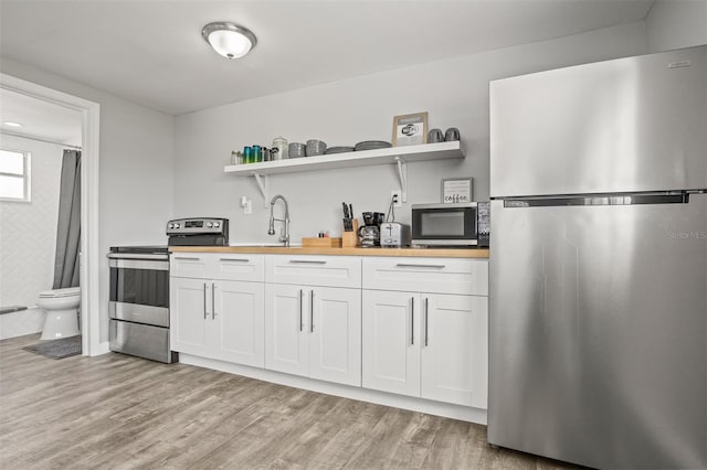 8820 Rocky Creek Dr, Tampa, FL 33615 - kitchen featuring wood counters, light hardwood / wood-style floors, stainless steel appliances, and white cabinets