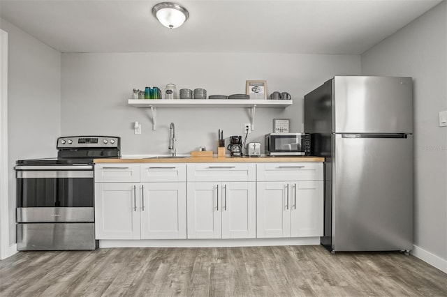 8820 Rocky Creek Dr, Tampa, FL 33615 - kitchen featuring stainless steel appliances, white cabinets, wood counters, light hardwood / wood-style floors, and sink