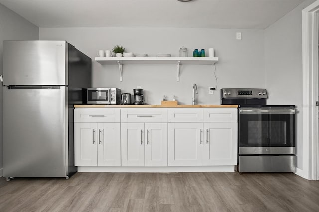 8820 Rocky Creek Dr, Tampa, FL 33615 - kitchen with light hardwood / wood-style flooring, butcher block counters, stainless steel appliances, sink, and white cabinetry