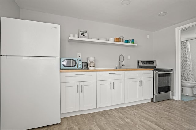 8820 Rocky Creek Dr, Tampa, FL 33615 - kitchen featuring white fridge, stainless steel range with electric stovetop, white cabinetry, and light wood-type flooring