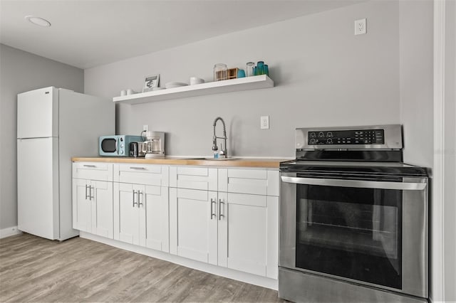 8820 Rocky Creek Dr, Tampa, FL 33615 - kitchen with electric stove, light wood-type flooring, white cabinets, white fridge, and sink