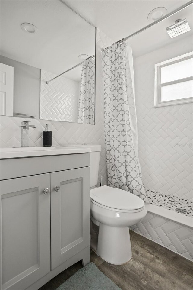 8820 Rocky Creek Dr, Tampa, FL 33615 - bathroom featuring hardwood / wood-style flooring, a shower with curtain, toilet, tile walls, and vanity