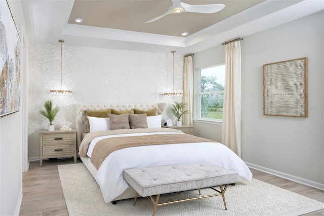 bedroom with a tray ceiling and wood-type flooring