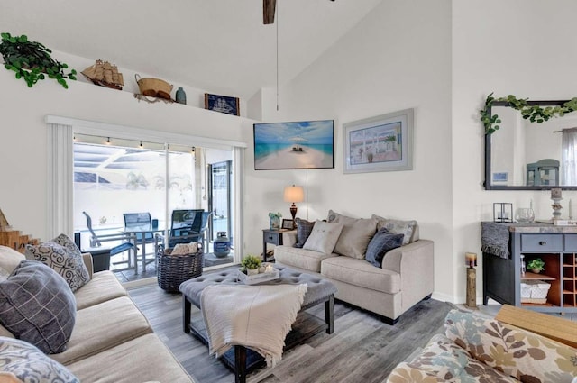 living room featuring high vaulted ceiling, wood finished floors, and baseboards