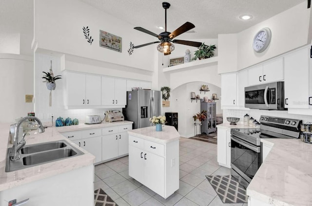 kitchen featuring stainless steel appliances, backsplash, light tile patterned flooring, a sink, and a textured ceiling