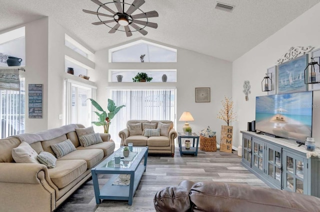 living room featuring visible vents, a ceiling fan, a textured ceiling, wood finished floors, and high vaulted ceiling