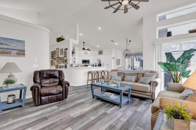 living room with high vaulted ceiling, recessed lighting, ceiling fan, and wood finished floors