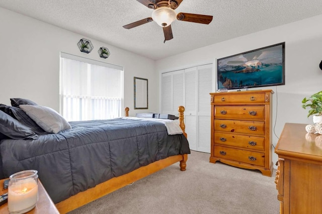 bedroom with a ceiling fan, a closet, light carpet, and a textured ceiling