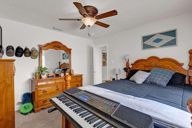 bedroom with a ceiling fan, light colored carpet, visible vents, and a textured ceiling