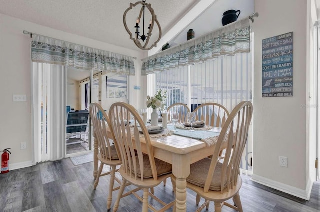 dining area featuring a notable chandelier, vaulted ceiling, a textured ceiling, wood finished floors, and baseboards