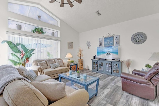 living area featuring high vaulted ceiling, a ceiling fan, visible vents, and wood finished floors