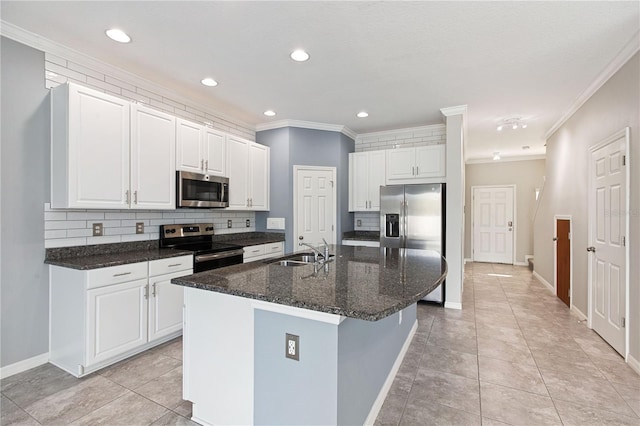 kitchen with appliances with stainless steel finishes, sink, dark stone countertops, white cabinets, and a center island with sink