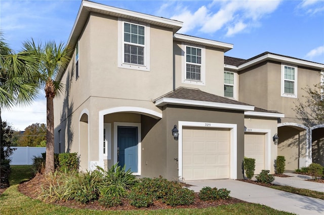 view of front of house with stucco siding, driveway, and fence